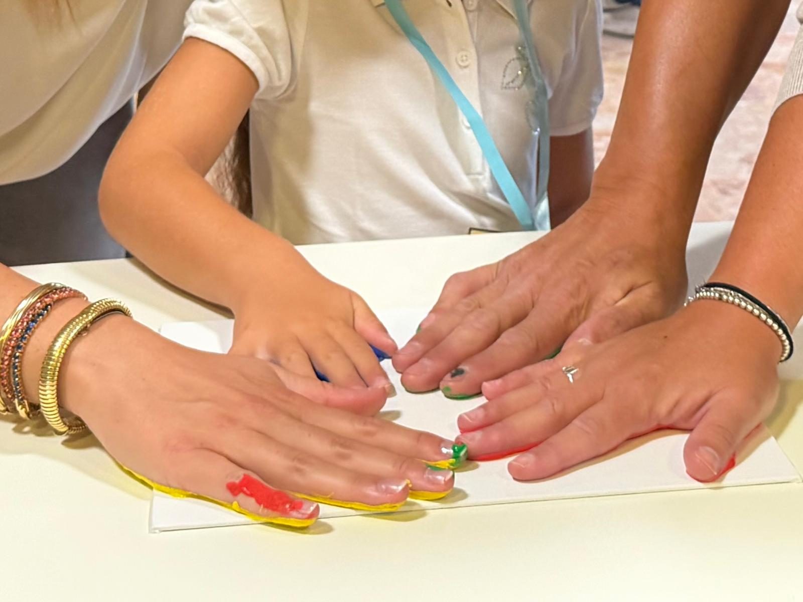 Mani di una bambina e delle maestre colorate durante un laboratorio